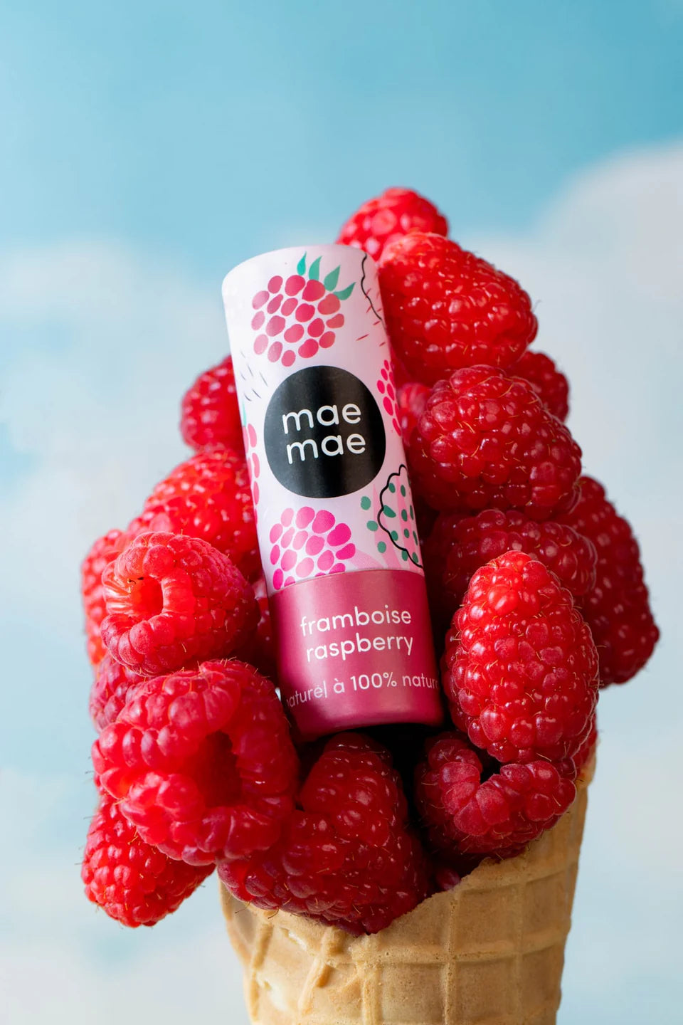 Baume à lèvres naturel framboise mae mae posé dans un cornet de framboises fraîches