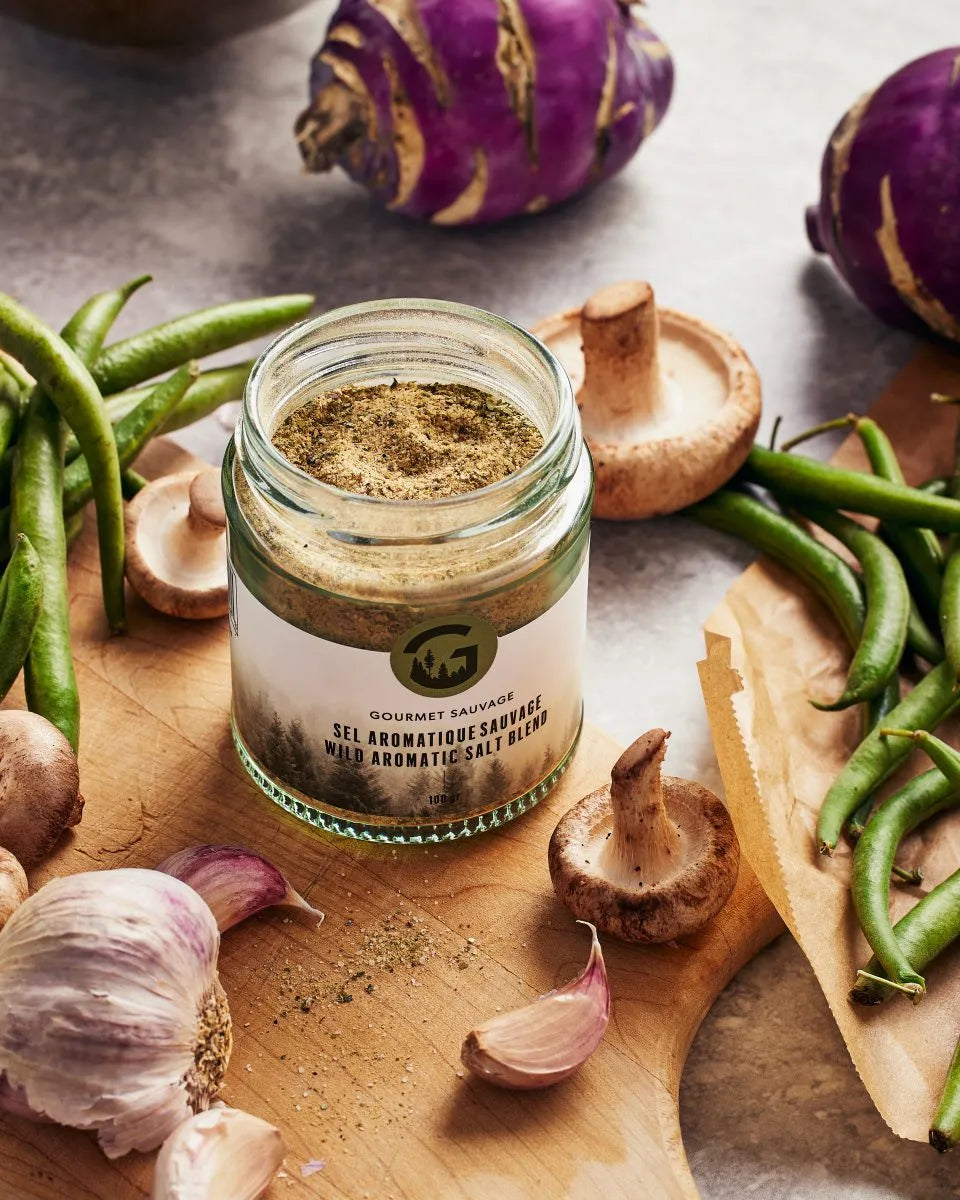 Sel aromatique sauvage Gourmet Sauvage en utilisation dans un décor naturel du Québec, ambiance cuisine, mettant en valeur un assaisonnement authentique et riche en saveurs