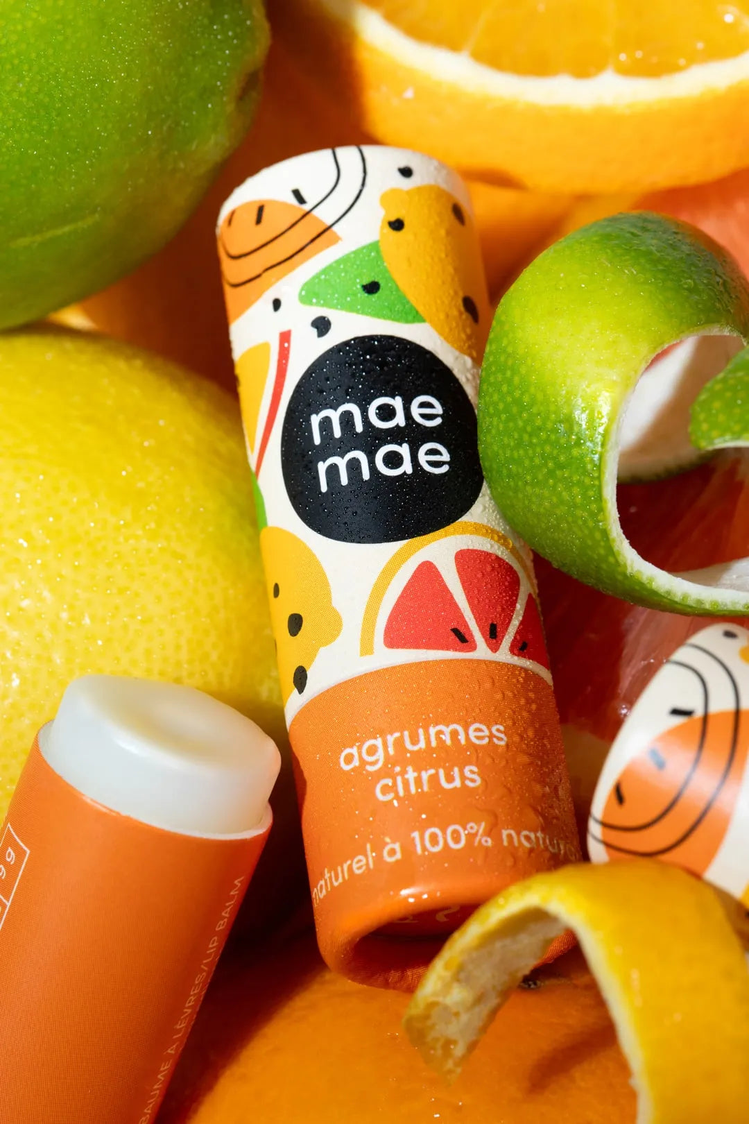 Baume à lèvres naturel aux agrumes mae mae entouré de citrons et oranges frais