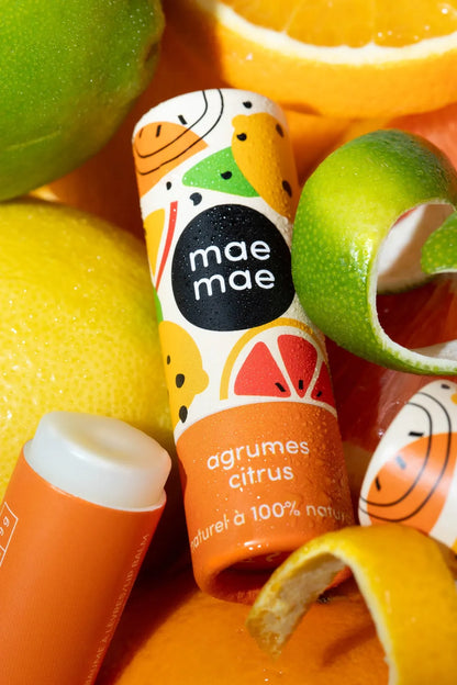 Baume à lèvres naturel aux agrumes mae mae entouré de citrons et oranges frais