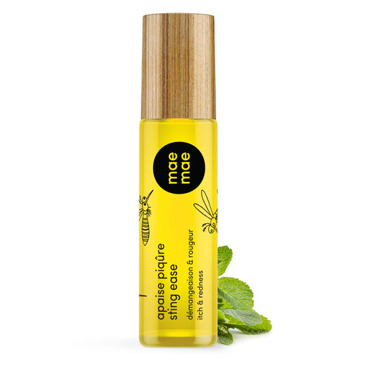 Roll‑on naturel Mae Mae apaise piqûres et chasse‑moustiques, flacon en verre jaune avec bille applicatrice et couvercle en bambou, présenté debout sur fond blanc avec des feuilles de menthe.