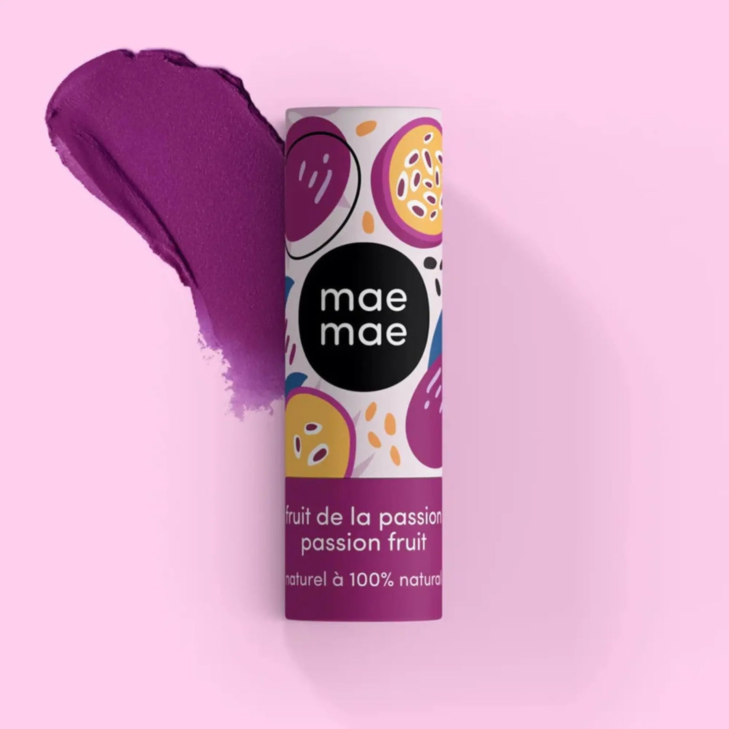 Baume à lèvres teinté Mae Mae fruit de la passion présenté avec une trace de texture mauve sur fond rose

