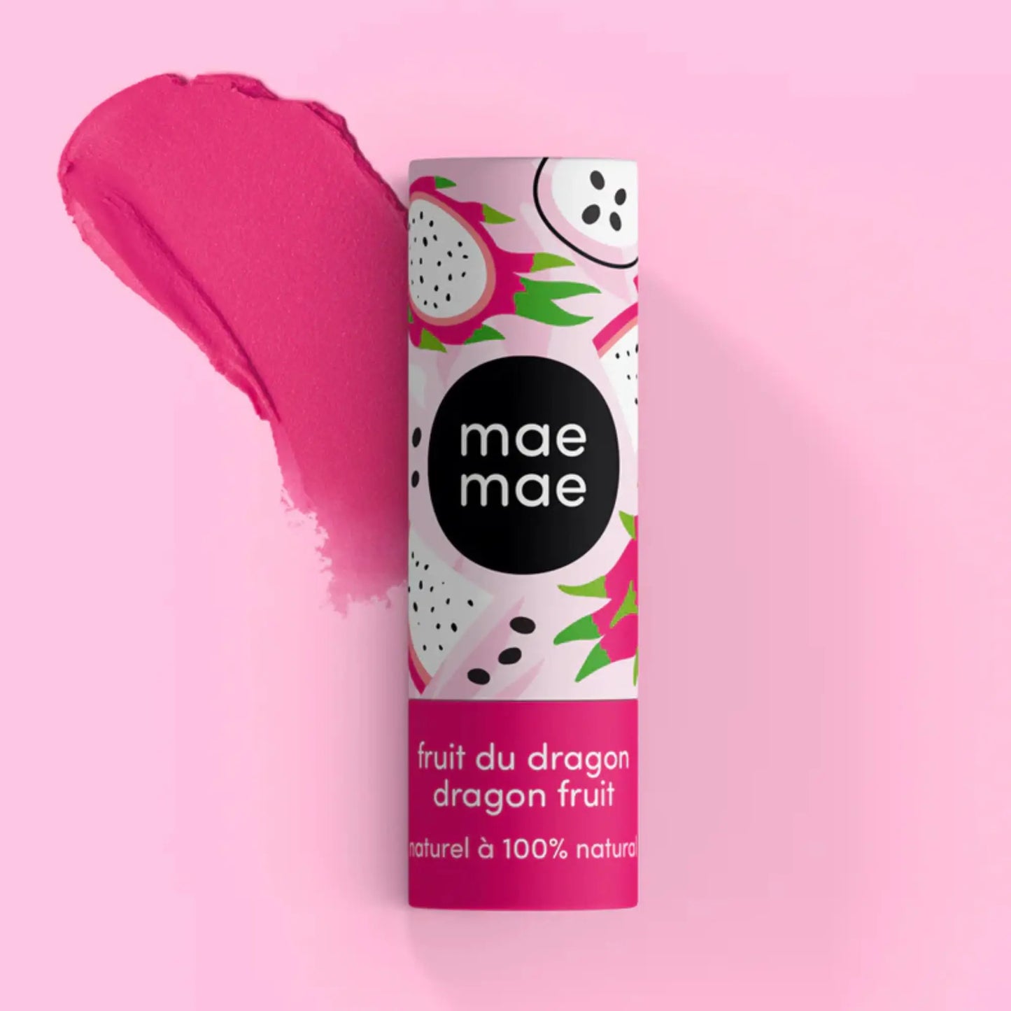 Baume à lèvres teinté au fruit du dragon Mae Mae posé debout sur un fond rose, avec un large coup de couleur rose vif derrière le tube pour illustrer la teinte.