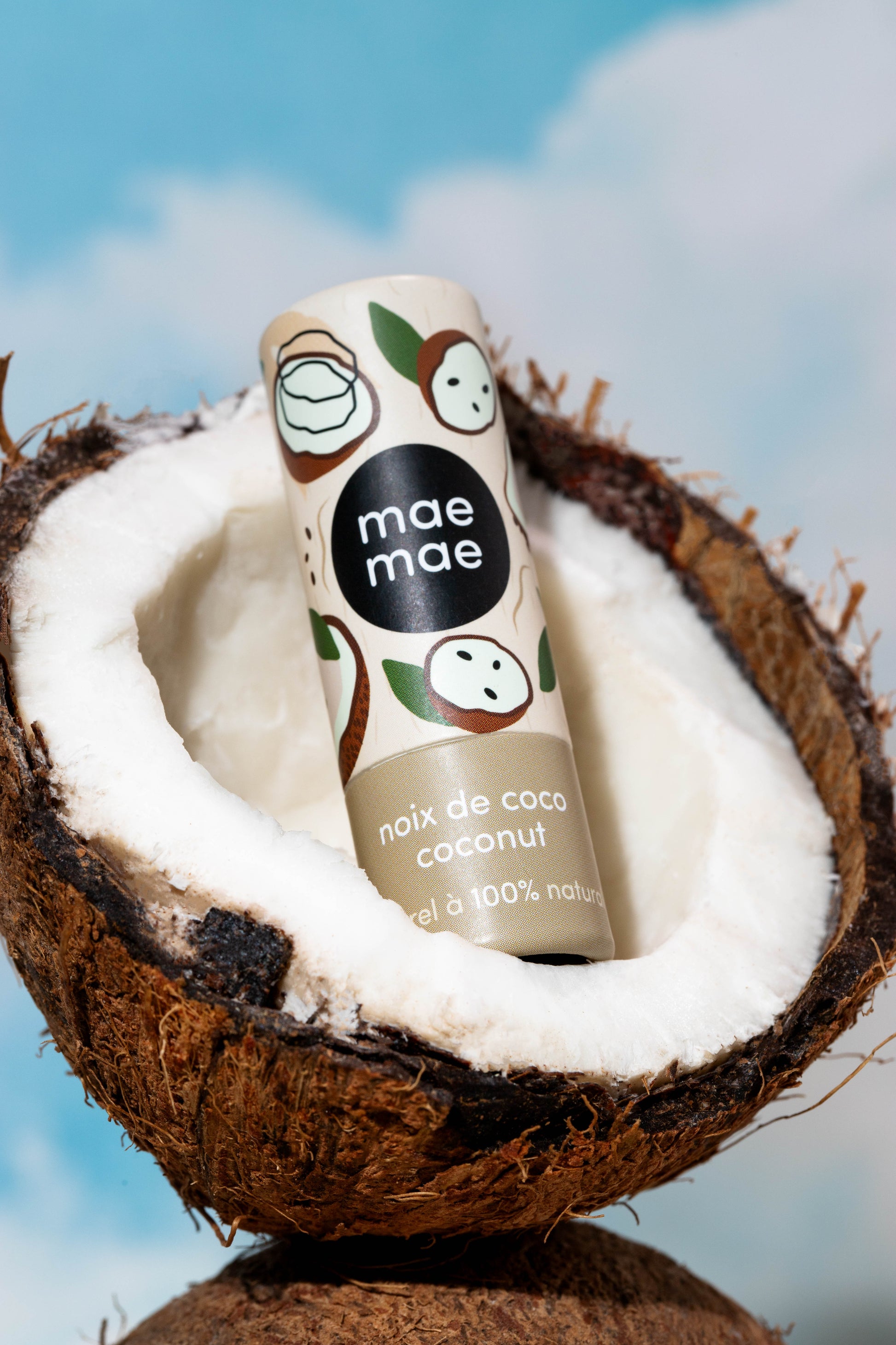 Baume à lèvres naturel à la noix de coco mae mae posé dans une noix de coco fraîche